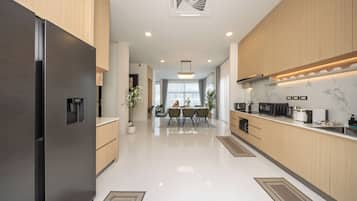 A modern kitchen with a stainless steel refrigerator, wooden cabinets, and a dining area with a table and chairs.