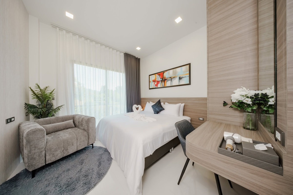 Una habitación de hotel moderna con cama, sofá, escritorio y un espejo grande.
