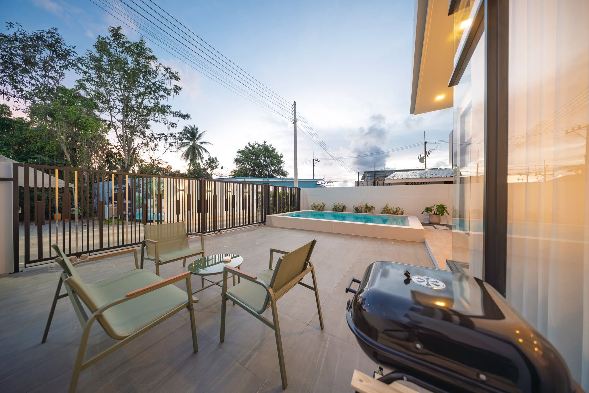 An outdoor patio with a pool, seating area, and a grill.