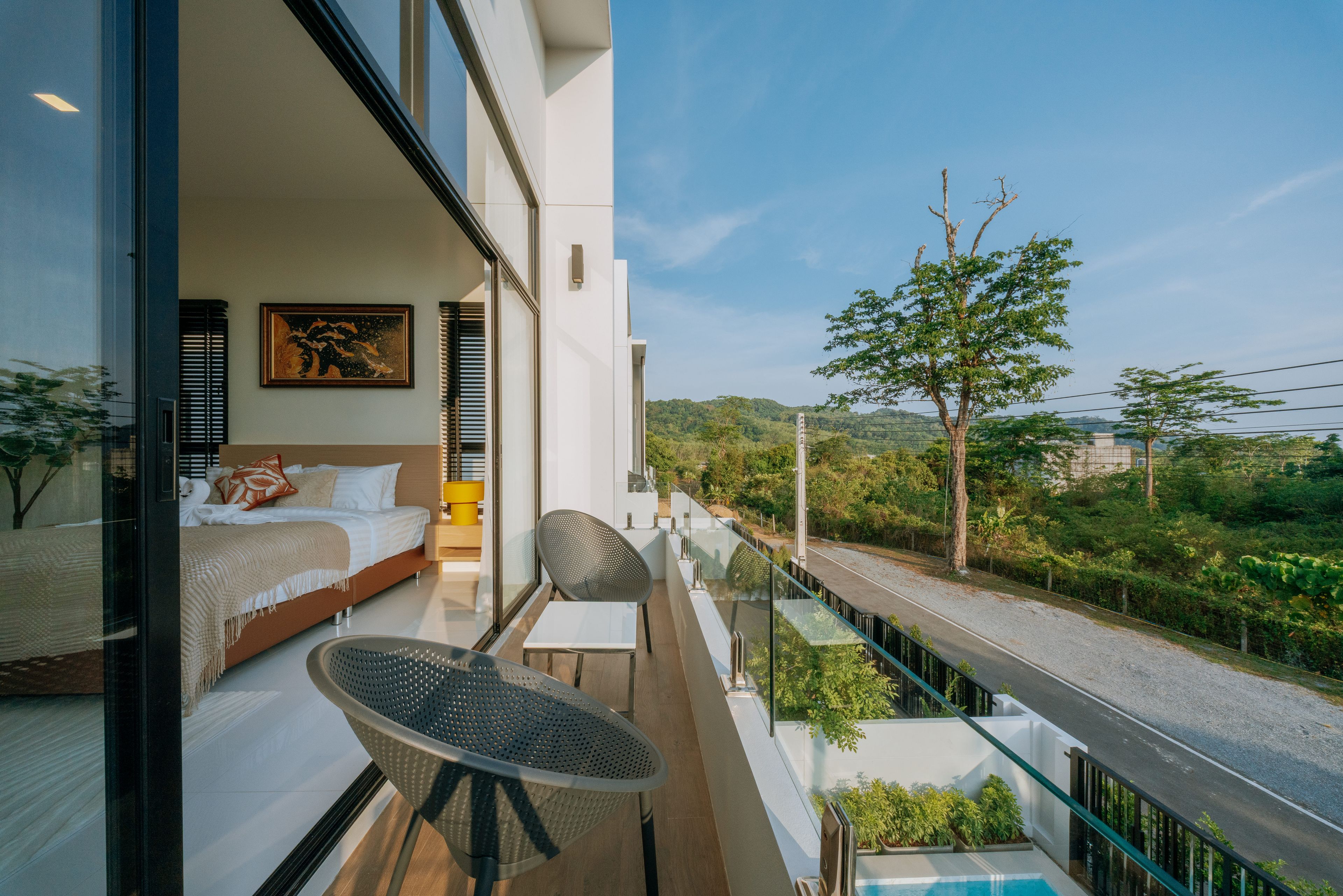 Un dormitorio moderno con una cama grande, un cuadro y un balcón con una silla y una mesa.