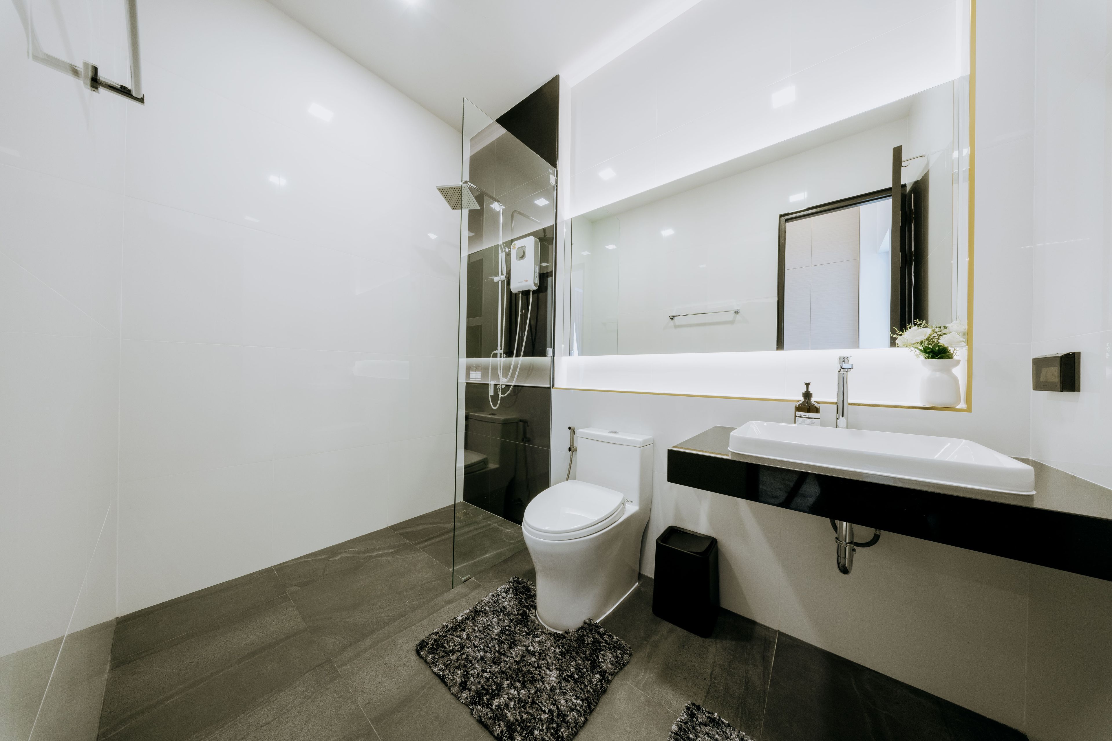 A modern bathroom with a toilet, bidet, and a large mirror above the sink.