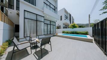 A modern outdoor patio with a pool, seating area, and a view of the surrounding landscape.
