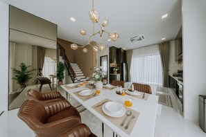 Un comedor moderno con una mesa grande, sillas de cuero marrón y un candelabro.