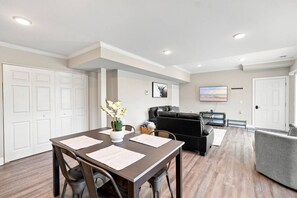 A modern living room with a dining area, a sofa, and a television.