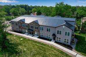 A multi-story residential building with a flat roof, large windows, and a covered front porch. - Spacious Modern 4BR/4BA First-Floor Accessible (Eggertsville)