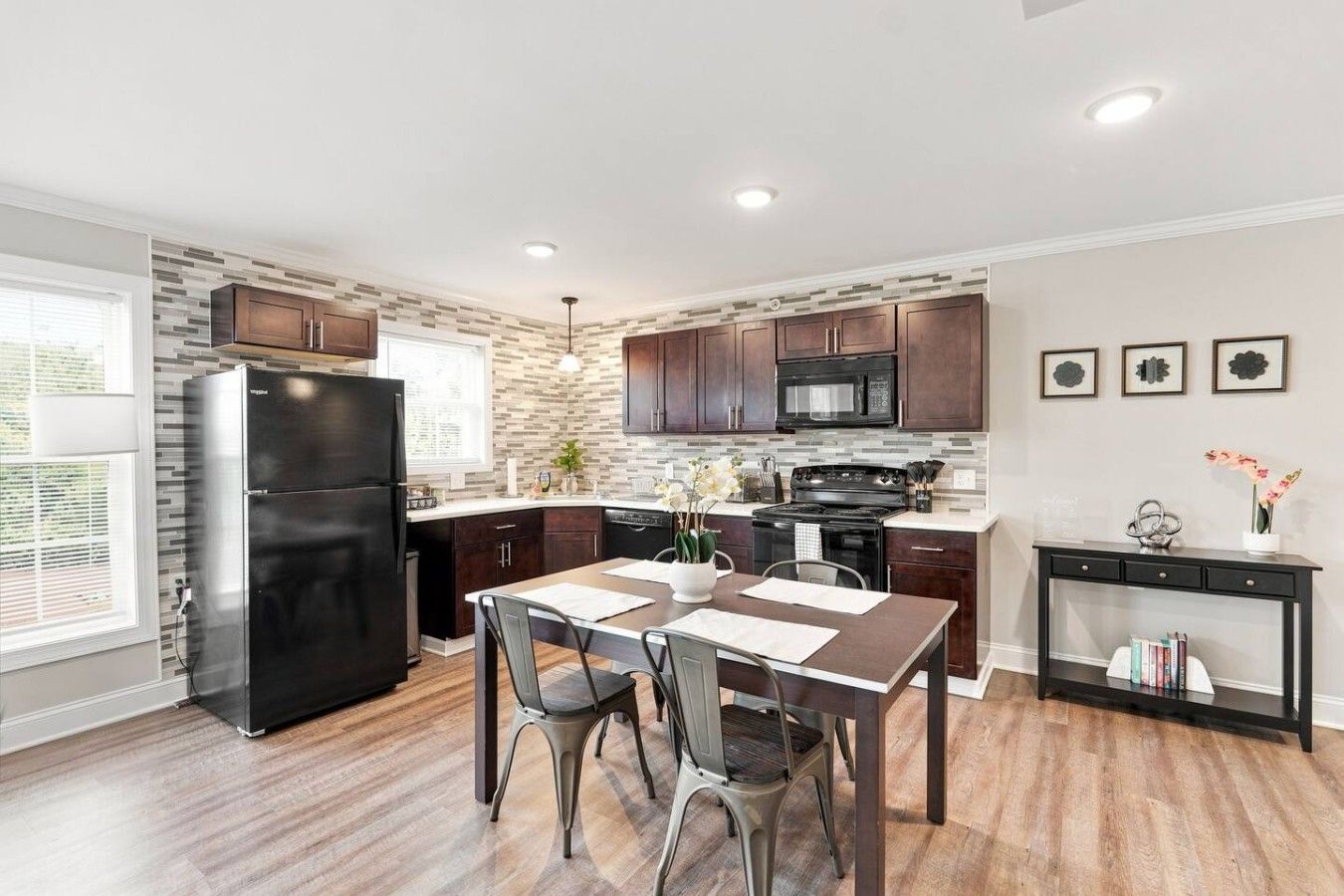 A modern kitchen with dark wooden cabinets, a stainless steel refrigerator, and a black stove.