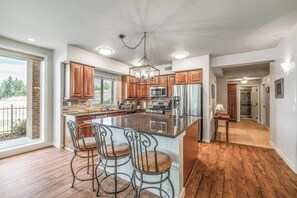 A modern kitchen with a large island, bar stools, and a view of the outdoors. - Gated Riverfront Condo W/ Private Boardwalk (Post Falls)
