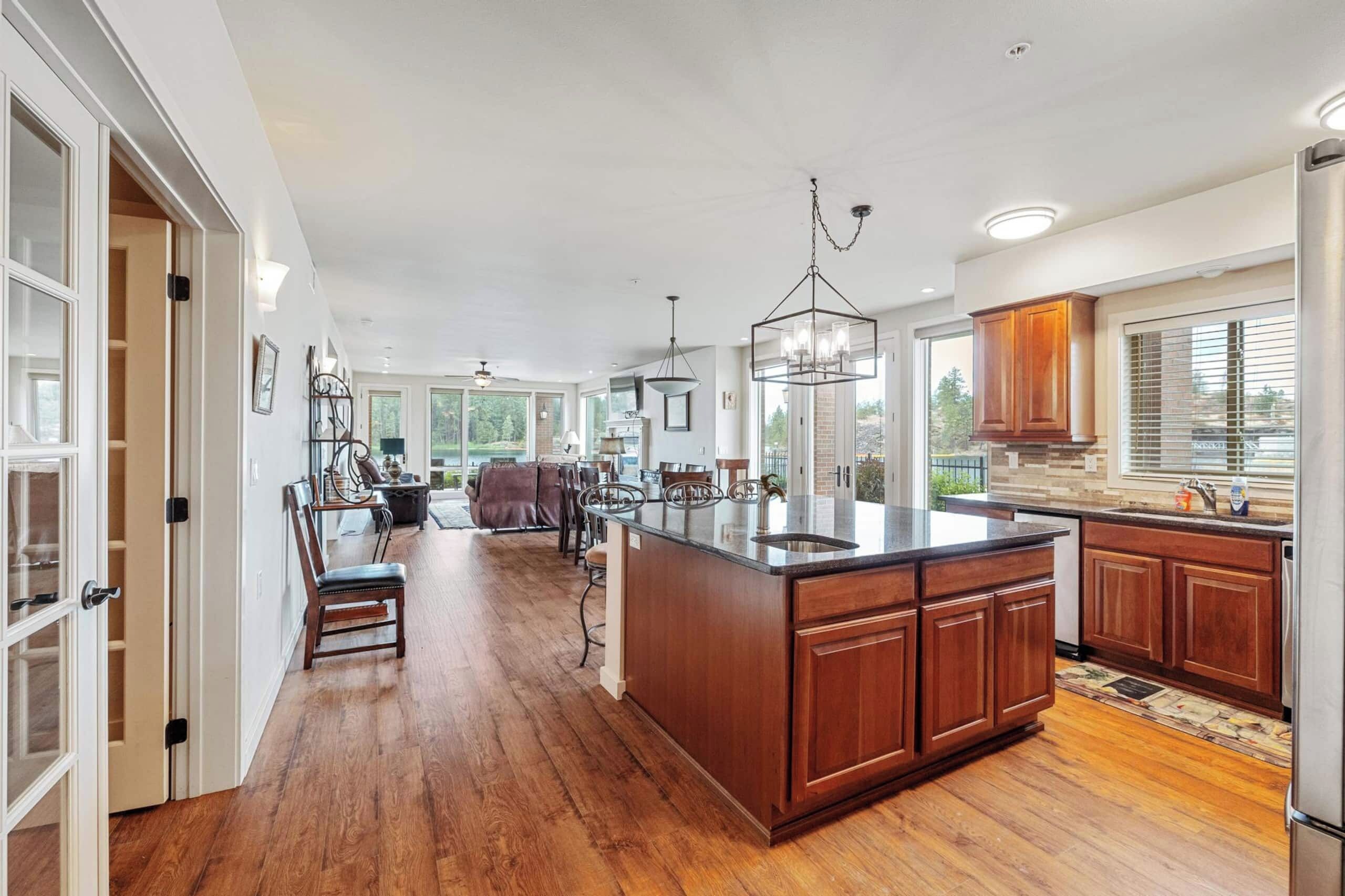 A spacious kitchen with a large island, wooden cabinets, and a view to the outdoors.
