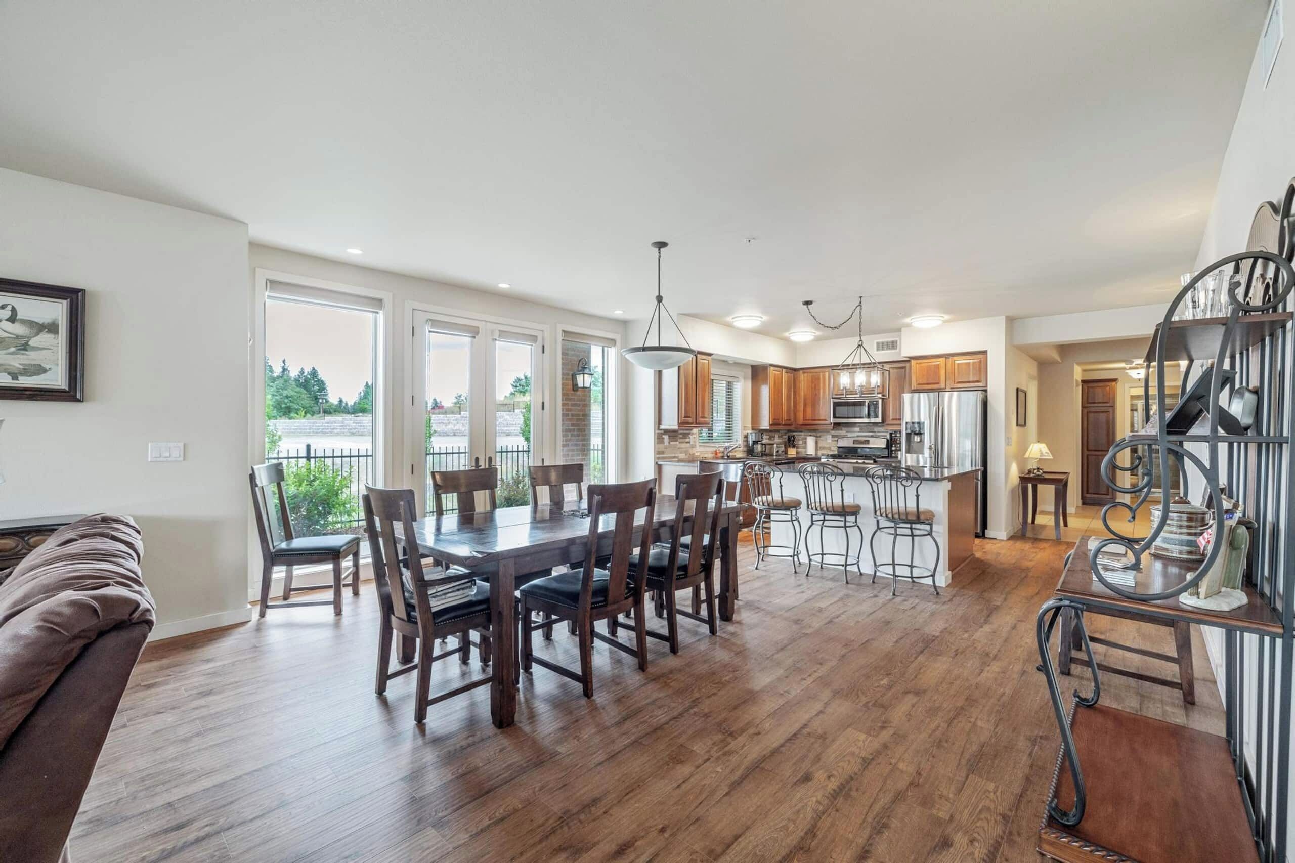 A spacious kitchen with a central island, wooden flooring, and a dining area with a large table and chairs.