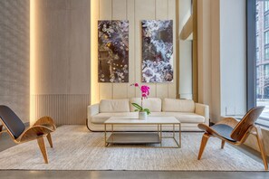 A modern living room with a sofa, two chairs, a coffee table, and two abstract paintings. - Blueground | Hell's Kitchen, gym, nr Hudson River (New York)