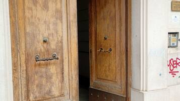 Puerta doble de madera con base de metal, que da a un pasillo con suelo de baldosas.