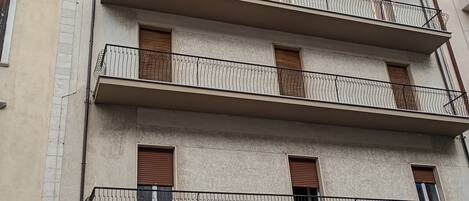 Un edificio de varios pisos con balcones, una puerta de garaje y grafitis.