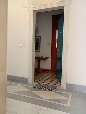 A hallway with a patterned floor, a chessboard, and a door leading to another room. - Roma 64 (Campobasso)