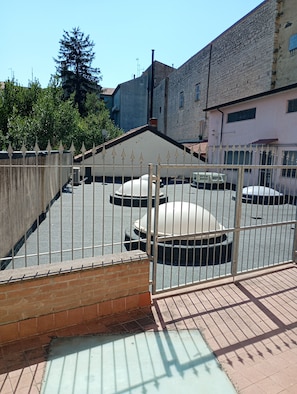 Un estacionamiento amurallado con un camino de acceso circular, rodeado de edificios y árboles.