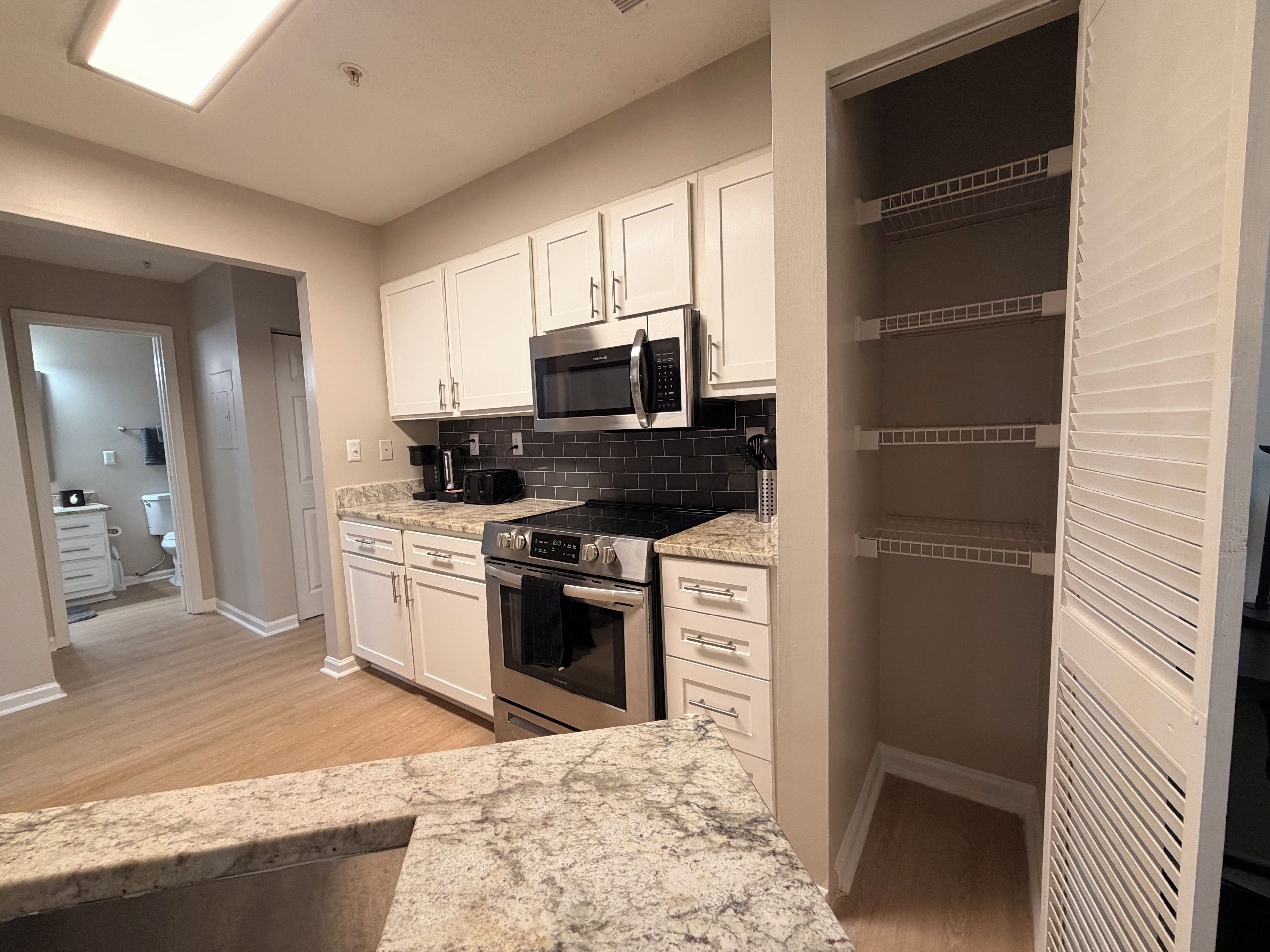 A kitchen with white cabinets, a microwave, a stove, and a countertop.
