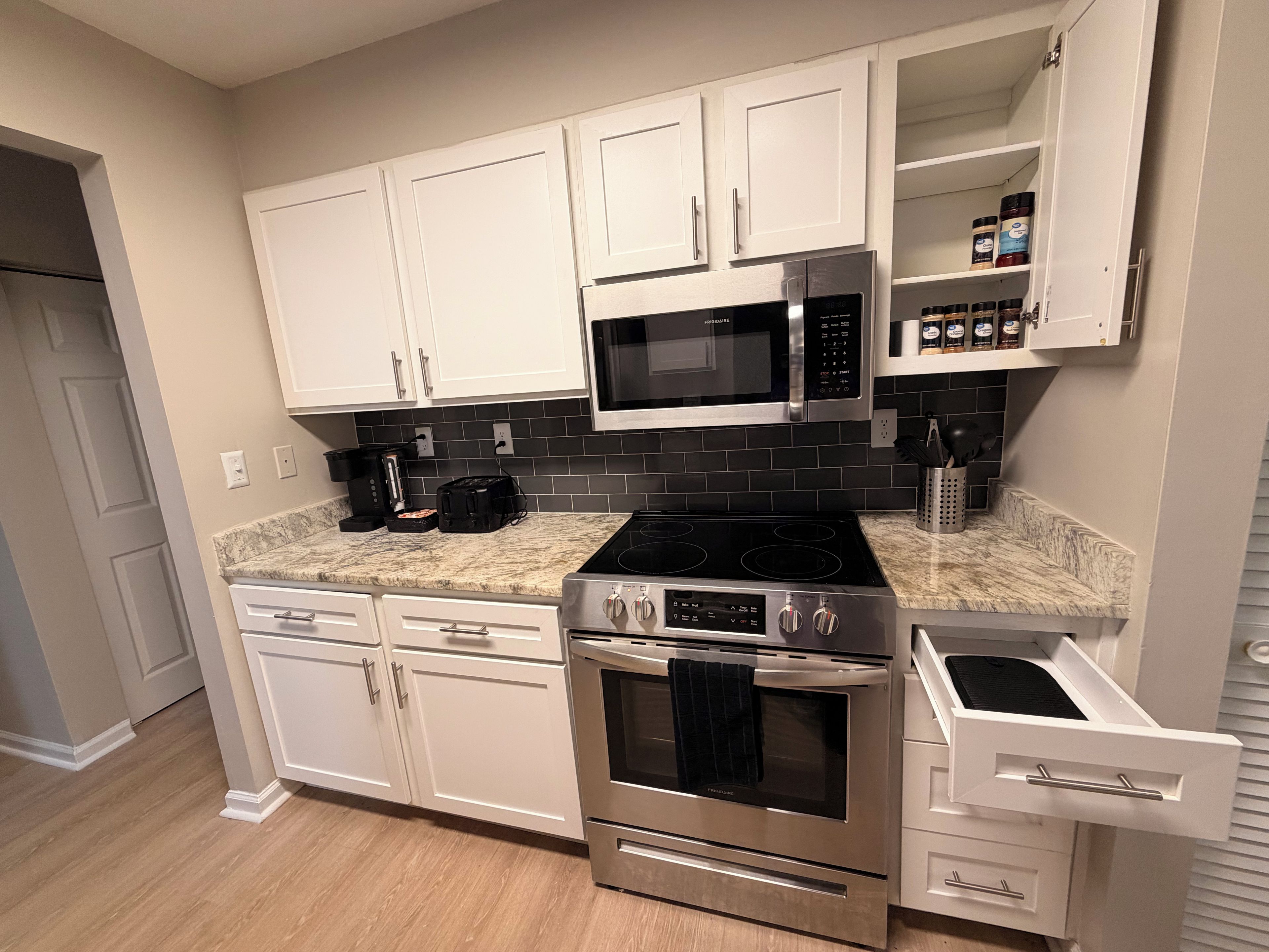A modern kitchen with white cabinets, a black microwave, a gas stove, and a built-in oven.