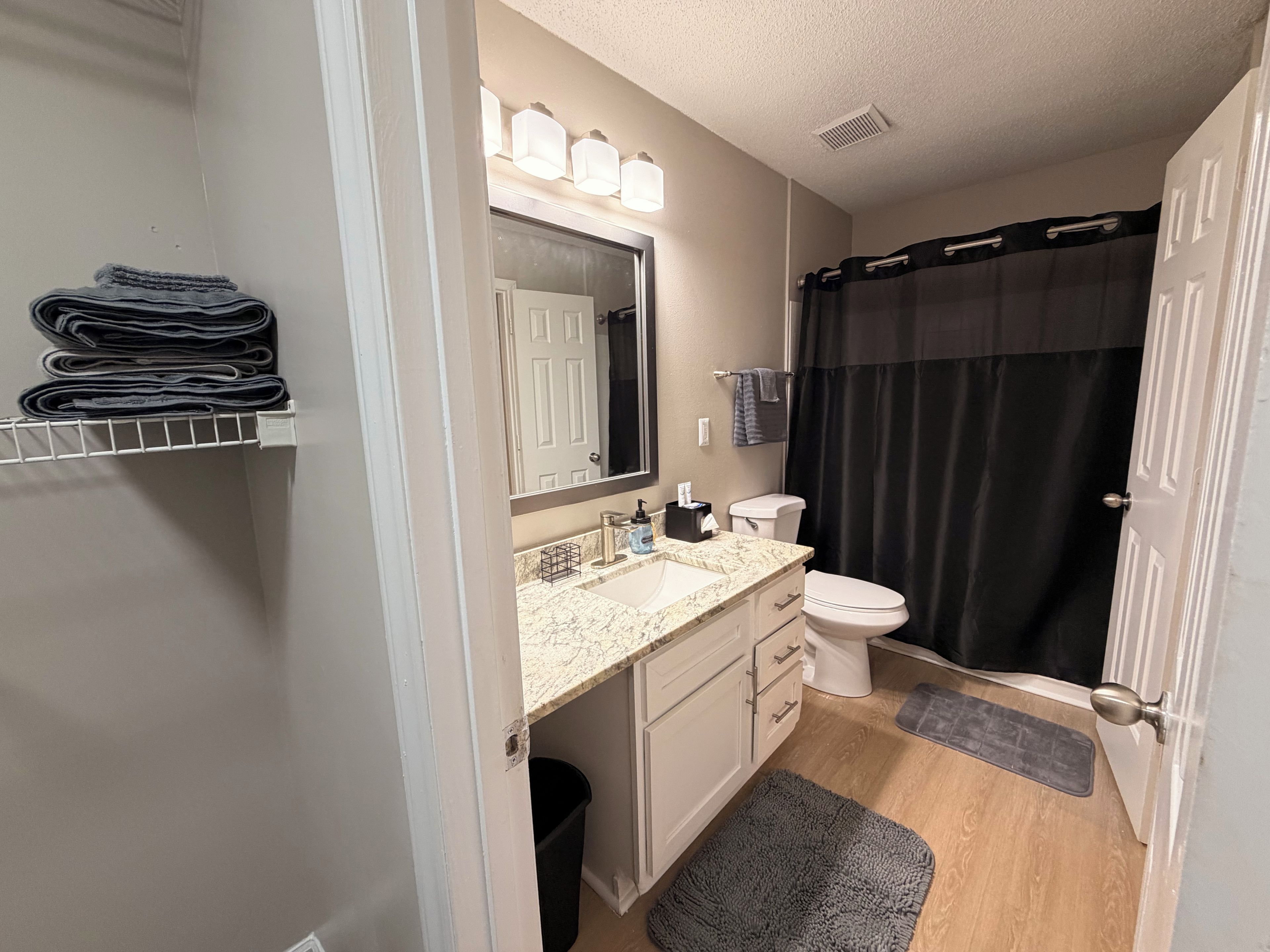 A bathroom with a sink, mirror, toilet, and shower curtain.