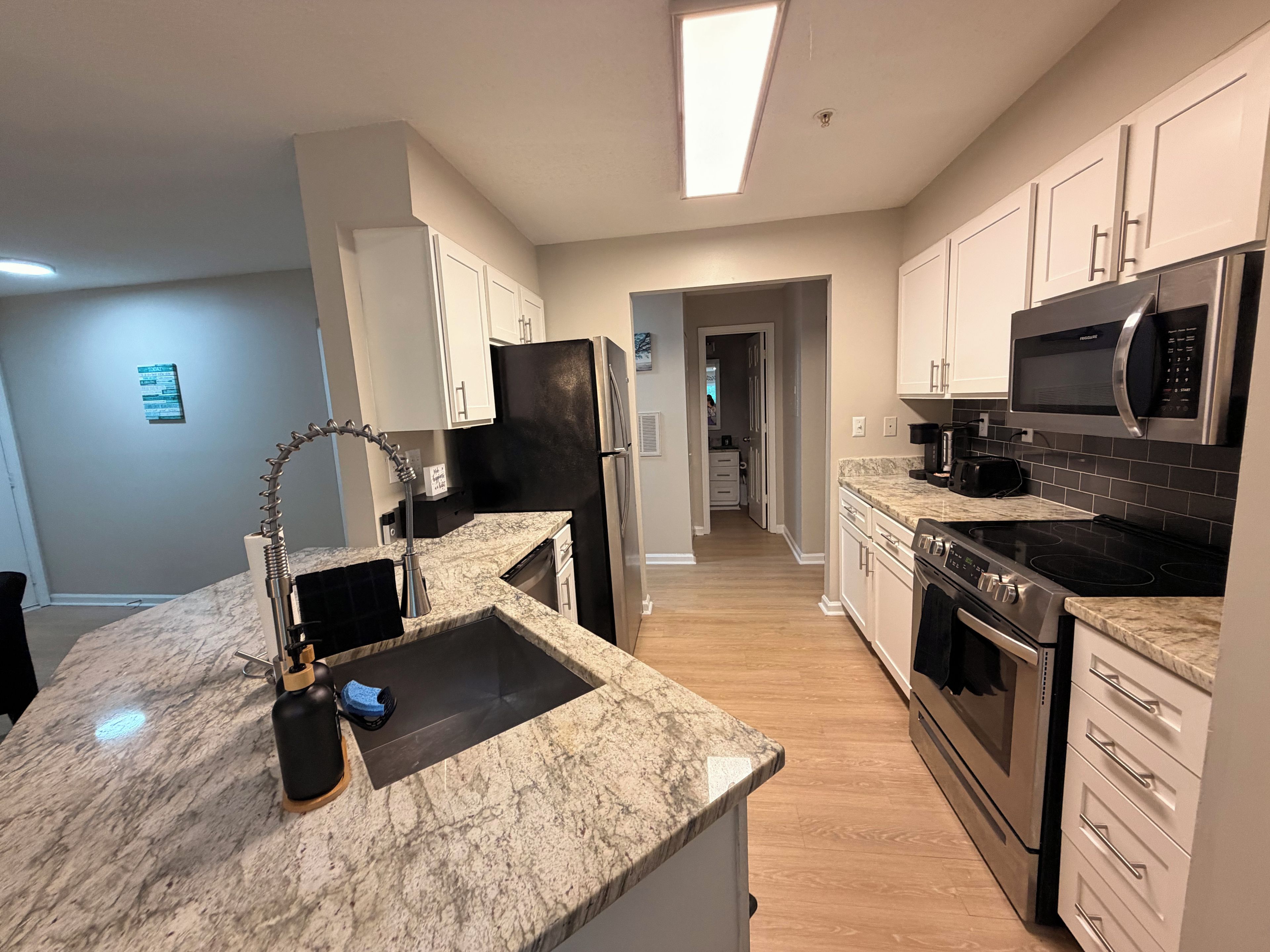 A modern kitchen with granite countertops, stainless steel appliances, and a walk-in pantry.