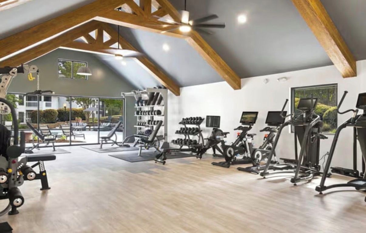 A gym with exercise equipment, a weight rack, and a large window.