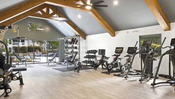 A gym with exercise equipment, a weight rack, and a large window.