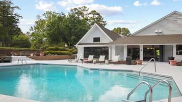 A swimming pool with lounge chairs and a covered patio area.