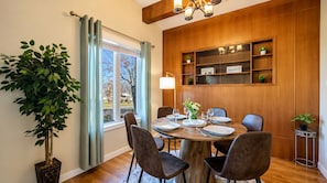 A dining area with a round table, chairs, a potted plant, and a built-in shelf with decorative items. - Bright Family Home | 10 mins to Airport & Downtown (Calgary)