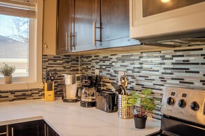 A kitchen with stainless steel appliances, a coffee maker, and a potted plant. - Bright Family Home | 10 mins to Airport & Downtown (Calgary)