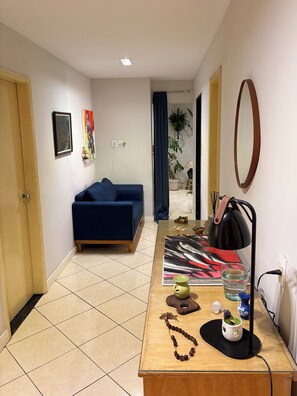 A room with a blue sofa, a wooden coffee table with decorative items, a mirror, and a door.