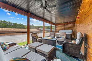 A covered outdoor seating area with wicker furniture, a fire feature, and a view of the surrounding landscape. - Near Outdoor Pool&Lazy River_Free Attraction Tickets_Private Hot Tub_Kids Room (Hollister)