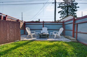 Ein Garten mit Grill, zwei Stühlen und einem Holzzaun.