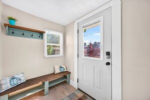Ein Flur mit einer Bank, einer Tür und einem Fenster mit Jalousien.