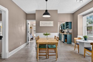A dining area with a wooden table and chairs, a pendant light, and a framed sign on the wall. - Roadmap Lodging: Craftsman 3BR, Near Downtown Indy (Indianapolis)