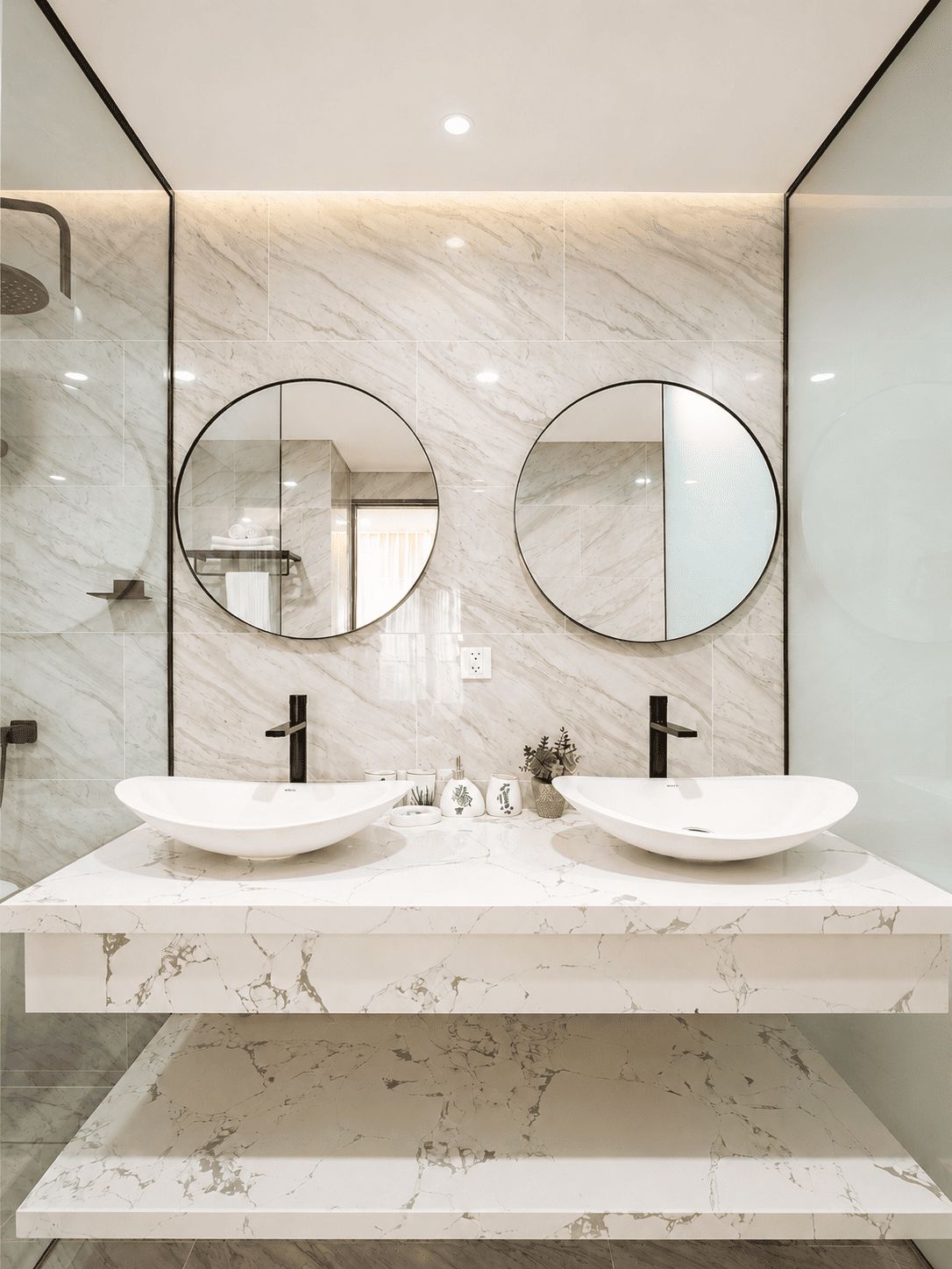 Une salle de bain avec deux lavabos, une douche et un miroir au-dessus des lavabos.