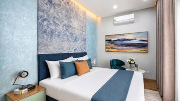 Un dormitorio moderno con una cama grande, una mesita de noche, aire acondicionado instalado en la pared, un cuadro y una silla.