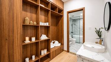 A modern bathroom with wooden shelving, a marble sink, and a glass shower enclosure.