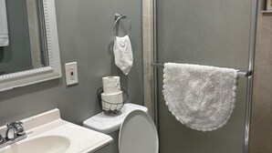 Kylpyhuone, jossa on wc, pesuallas, peili ja suihkukaappi.