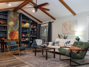 A living room with a ceiling fan, a bookshelf, a sofa, a coffee table, and a green armchair.