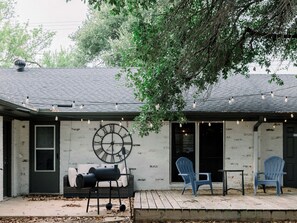 Una casa con porche, un reloj grande al aire libre y mobiliario de exterior.