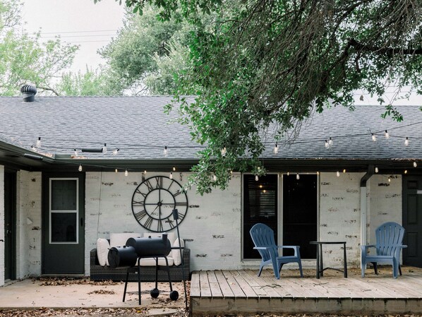 A house with a porch, a large outdoor clock, and outdoor seating.