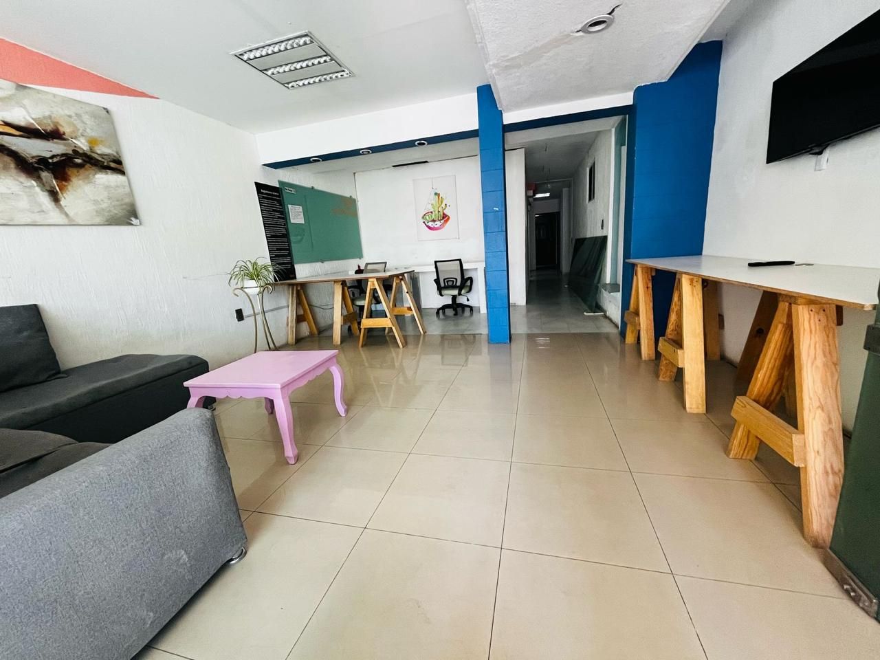 Un interior moderno con un sofá, una mesa rosa y un escritorio de madera.