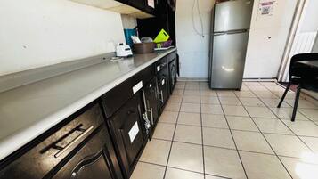 Cocina con refrigerador de acero inoxidable, encimera blanca y gabinetes negros.