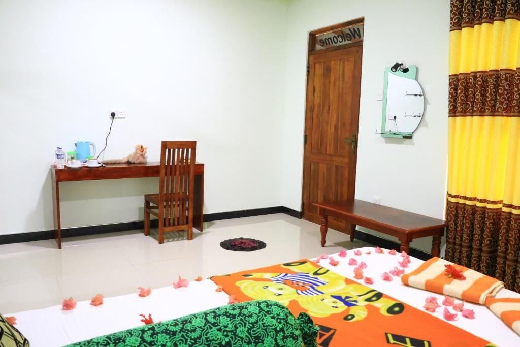 A room with a bed, a desk, a chair, a door, and a mirror on the wall.