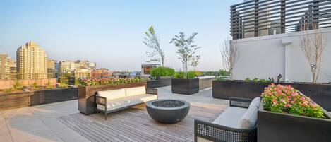Eine Dachterrasse mit Sitzgelegenheiten, Pflanzgefäßen und Blick auf die Stadtlandschaft.