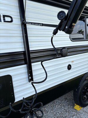 A section of a vehicle with a black frame and a white panel, featuring a black cable and a speaker.