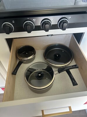 A drawer with three pots and pans.