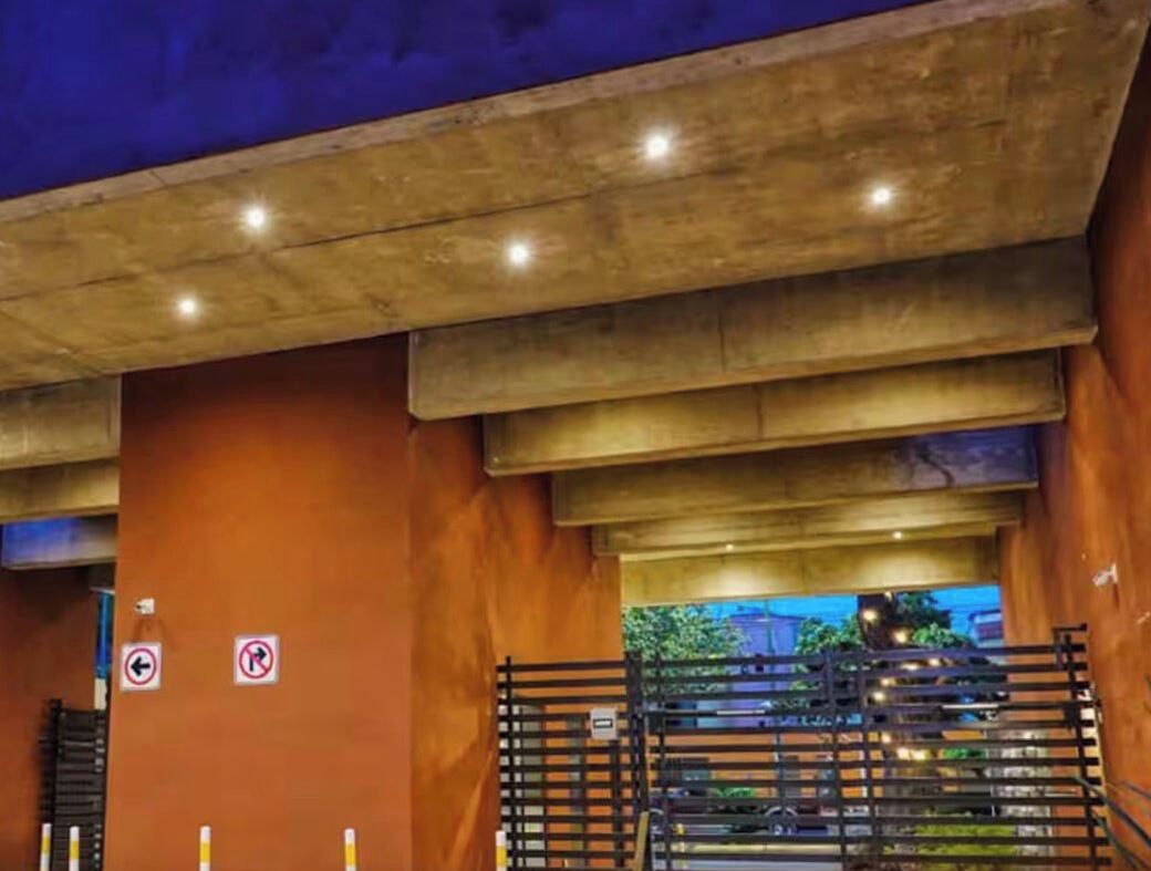 L’entrée d’un hôtel avec un plafond en béton, un mur en bois et un portail en métal.
