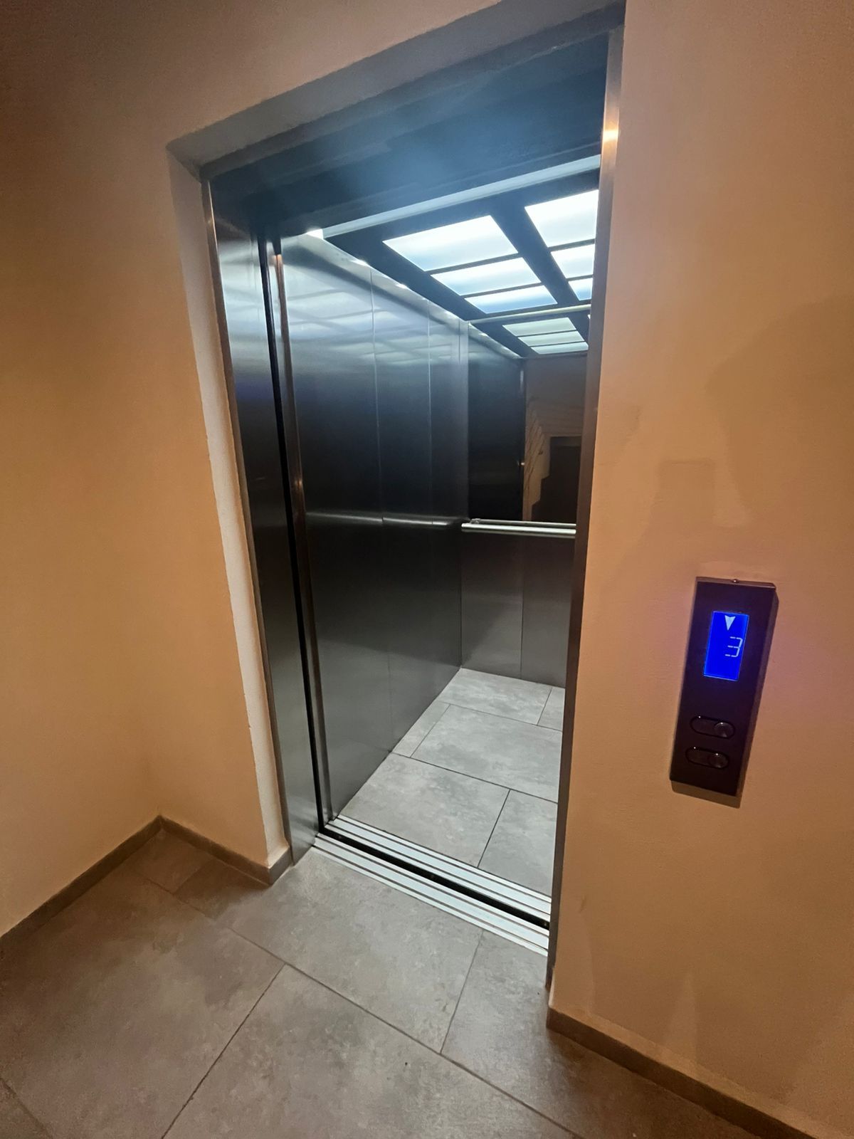 An elevator with a digital display and a glass door.