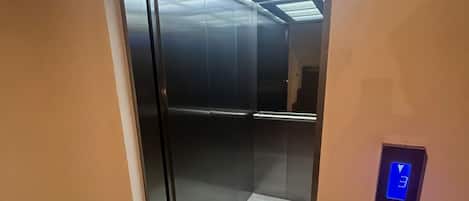 Un ascenseur doté d’un écran numérique et d’une porte en verre.