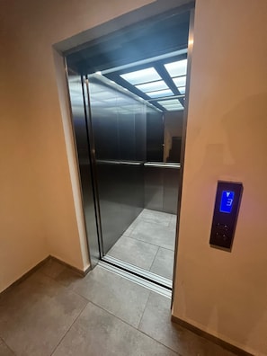 Un ascenseur doté d’un écran numérique et d’une porte en verre.