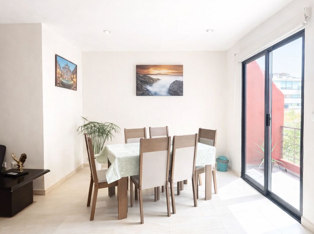 A dining area with a table set for four, a potted plant, and artwork on the walls.
